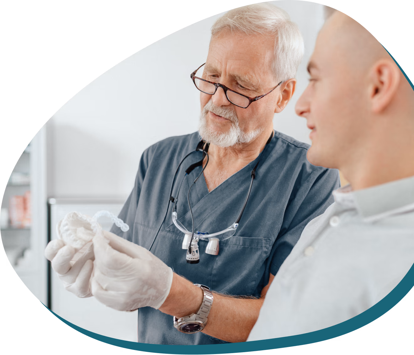 Dr. Otto von der Heide erklärt jungem Patienten die Funktionsweise einer transparenten Zahnschiene zur Zahnkorrektur